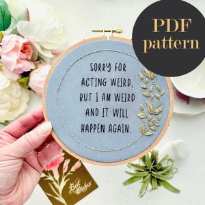 Puede incluir: Un aro de bordado azul con el texto "SORRY FOR ACTING WEIRD, BUT I AM WEIRD AND IT WILL HAPPEN AGAIN." en letras negras y bordado dorado de hojas alrededor del texto.