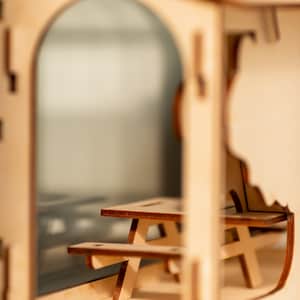Peut inclure: Une maison miniature en bois avec une petite table de pique-nique en bois &agrave; l'int&eacute;rieur. La maison est en bois brun clair et a une fen&ecirc;tre en plastique transparent.