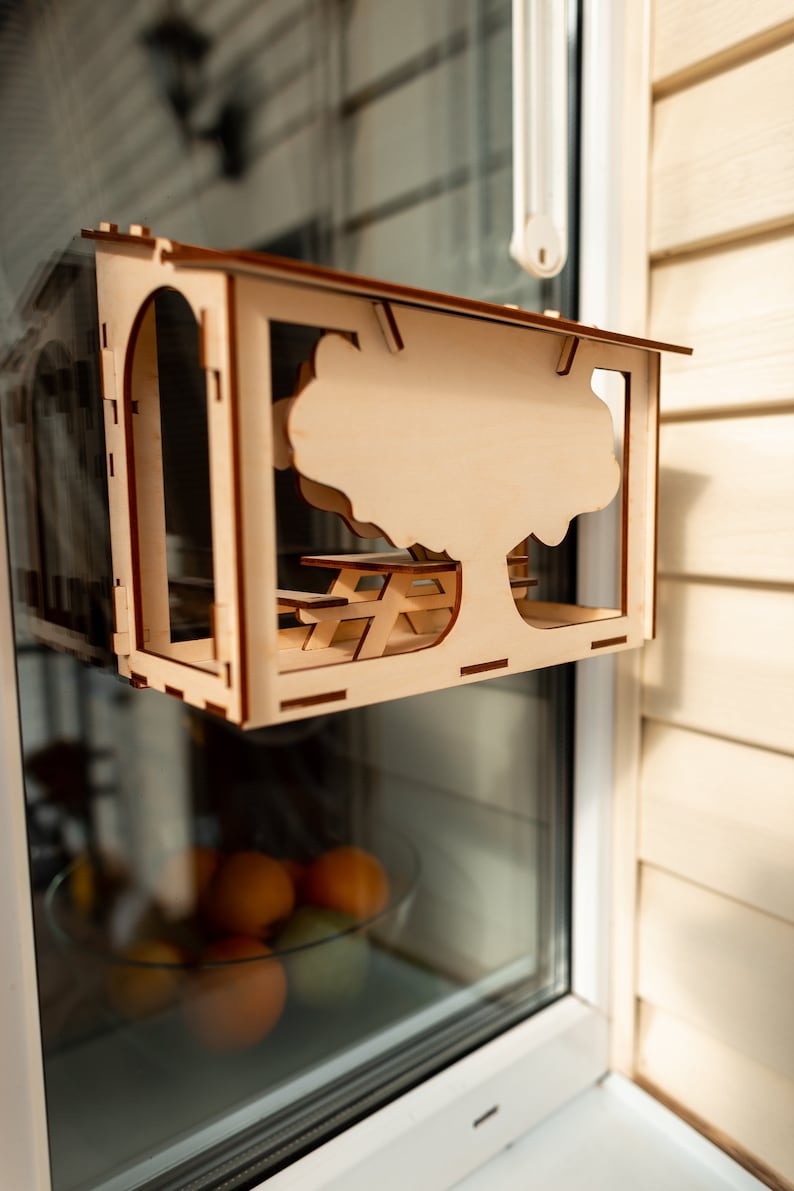 Peut inclure: Une maisonnette en bois en forme de petite cabane avec une d&eacute;coupe d'arbre et de table de pique-nique. La maisonnette est accroch&eacute;e &agrave; une fen&ecirc;tre.