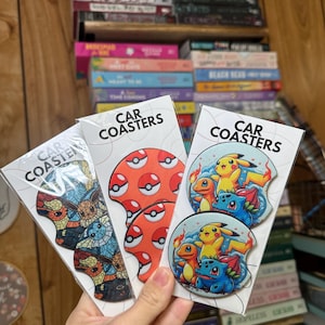 May include: Three sets of car coasters featuring Pokémon characters. The first set features a mosaic design of Eevee and its evolutions. The second set features a red Poké Ball design. The third set features a blue and yellow design of Pikachu and its evolutions.