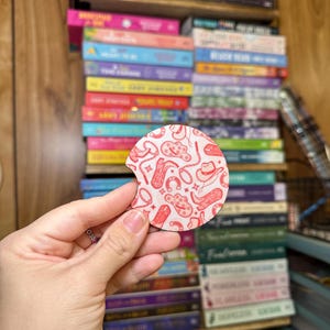 May include: A round, red and white coaster with a cowboy boot, horseshoe, and hat pattern.