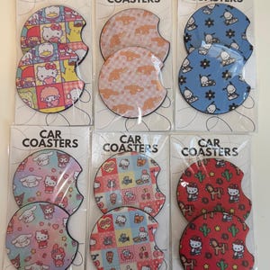 May include: Six sets of two circular car coasters in clear plastic packaging, each labeled CAR COASTERS. The coasters feature various colorful Sanrio character patterns, including Hello Kitty, Cinnamoroll, and Pochacco, with notched edges.