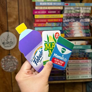 May include: Three colorful product labels, one for a purple cleaning product called "Fabuloso", one for a yellow corn product called "Maiz", and one for a green medicine product called "MamaRub".