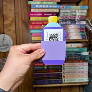 May include: A purple and blue paper bottle with a yellow lid and a QR code. The bottle has the text "To Connect!" and "Tumblers, Glass Cups, Toppers & More" printed on it.
