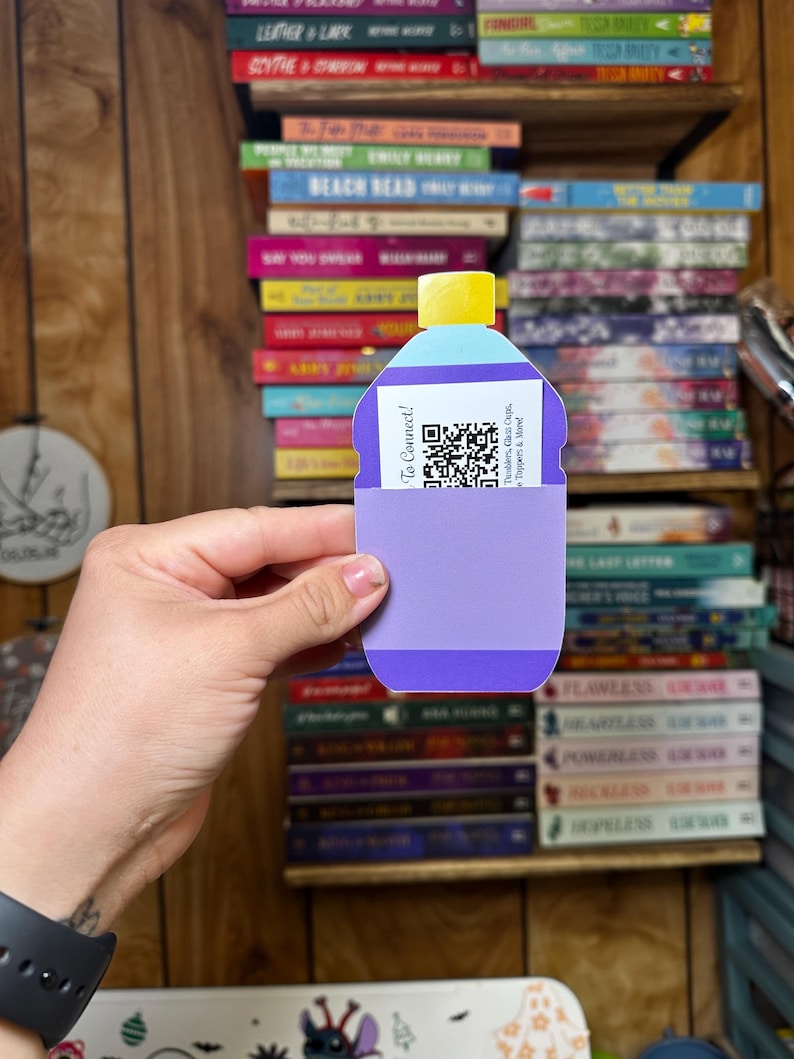 May include: A purple and blue paper bottle with a yellow lid and a QR code. The bottle has the text "To Connect!" and "Tumblers, Glass Cups, Toppers & More" printed on it.