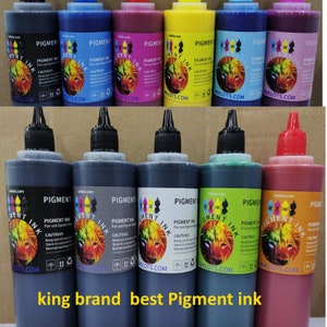 May include: A set of ten bottles of pigment ink for printers. The bottles are labeled "Pigment Ink" and have a variety of colors, including black, red, yellow, blue, green, and magenta. The bottles are arranged in two rows of five. The text "king brand best Pigment ink" is printed below the bottles.