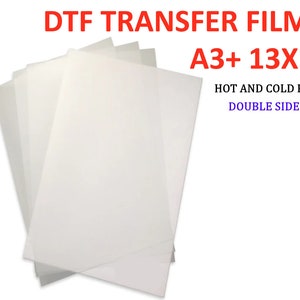 May include: A stack of white DTF transfer film sheets in A3+ size (13x19 inches). The film is double-sided and can be peeled hot or cold.