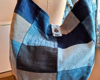May include: A patchwork denim shoulder bag in various shades of blue and gray. The bag features a button closure and a curved design. The denim is pieced together in a geometric pattern, creating a unique and stylish accessory.