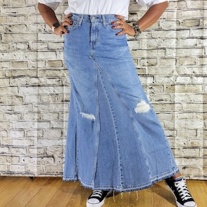 May include: A long denim skirt with distressed details and a flared silhouette. The skirt is a light blue wash and has a high waist.