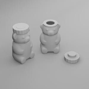May include: Three gray bear-shaped honey jars, one with a lid, one without, and a separate lid. The jars have a classic design, with a round body, small arms, and a bear face. The lid is round with a ridged edge.