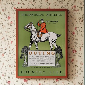 May include: A vintage magazine cover for "Outing", an illustrated magazine of sport, travel, adventure, and country life. The cover features a man in a red hunting jacket riding a white horse through a green forest. The text on the cover reads "International Athletics", "October", "Outing", "An Illustrated Magazine of Sport Travel Adventure and Country Life", "Edited by Caspar Whitney", "New York & London", and "Country Life".