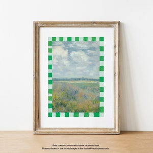 May include: A framed landscape painting of a field with a cloudy sky. The frame is a light brown wood with a green and white checkered border.