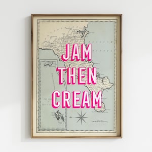 May include: Framed vintage-style map print with the text "JAM THEN CREAM" in bright pink. The map is in shades of green and beige, with a compass rose at the bottom. The frame is a warm brown.