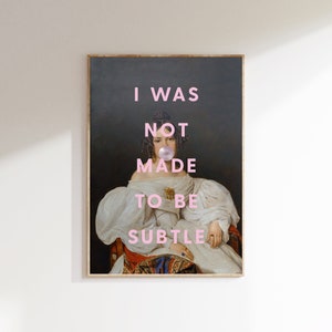 May include: A painting of a woman in a white dress with a pink bubble gum in her mouth. The text "I WAS NOT MADE TO BE SUBTLE" is written in pink letters on the painting.