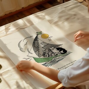 May include: A whimsical illustration of cats sailing on a green boat with a patchwork sail. The artwork features a yellow sun, seagulls, and the text "The Pussycat went to sea..." on a cream-colored background. The image is held by a person.