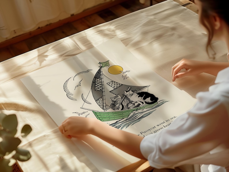 May include: A whimsical illustration of cats sailing on a green boat with a patchwork sail. The artwork features a yellow sun, seagulls, and the text "The Pussycat went to sea..." on a cream-colored background. The image is held by a person.