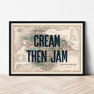 May include: A vintage map of Devon, England, with the text "CREAM THEN JAM" superimposed over it. The map is framed in black and has a white background.