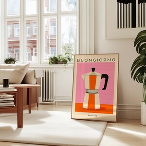 Puede incluir: Un cuadro enmarcado con una ilustraci&oacute;n estilizada de una cafetera italiana en naranja, blanco y negro sobre un fondo rosa. La palabra "BUONGIORNO" est&aacute; en la parte superior, con "ESPRESSO" en la parte inferior. El cuadro est&aacute; en un sal&oacute;n moderno y luminoso.