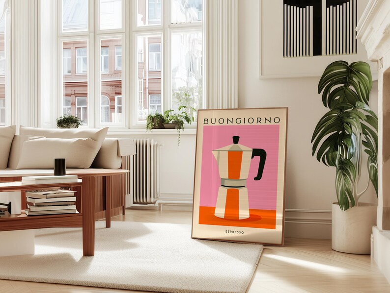 Puede incluir: Un cuadro enmarcado con una ilustraci&oacute;n estilizada de una cafetera italiana en naranja, blanco y negro sobre un fondo rosa. La palabra "BUONGIORNO" est&aacute; en la parte superior, con "ESPRESSO" en la parte inferior. El cuadro est&aacute; en un sal&oacute;n moderno y luminoso.
