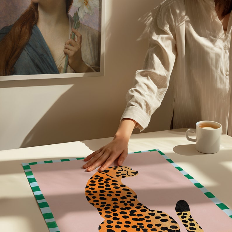 May include: A pink and green patterned poster with a stylized illustration of a cheetah in orange and black. The cheetah is sitting with its tail curled around its body.