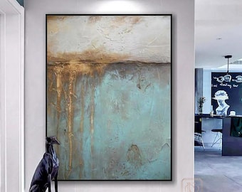 May include: Abstract painting with a textured, layered look. The painting features shades of blue, green, and gold. The painting is framed in a black frame and is hanging on a white wall.