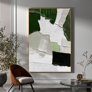 Puede incluir: Pintura abstracta con pinceladas verdes, blancas y negras. La pintura está enmarcada en un marco dorado.