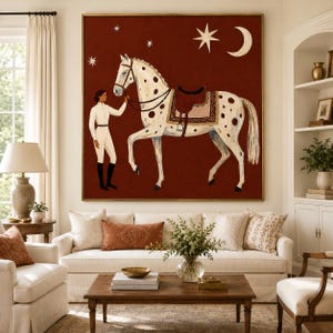 May include: A large square wall art piece featuring a white spotted horse with a brown saddle and a rider in white equestrian attire. The background is a deep rust red color decorated with a white crescent moon and several four-pointed stars.