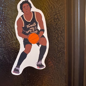 May include: A black and white illustration of a basketball player wearing a black jersey with the word "Toronto" and the number "3" on it. The player is dribbling a basketball and wearing black shorts and black sneakers.