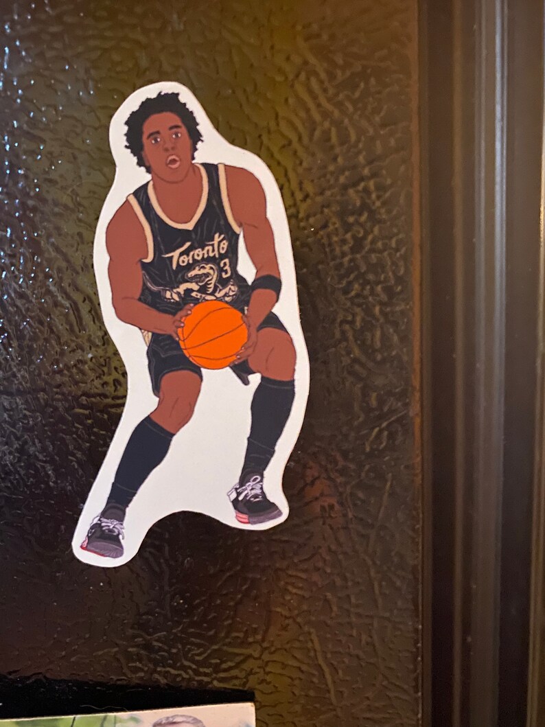 May include: A black and white illustration of a basketball player wearing a black jersey with the word "Toronto" and the number "3" on it. The player is dribbling a basketball and wearing black shorts and black sneakers.