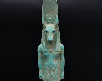 May include: A turquoise green statue of the Egyptian god Apis, depicted as a bull with a human body. The statue is standing on a base with hieroglyphs.