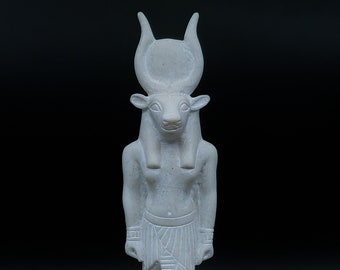 May include: White statue of an Egyptian god with a bull's head, standing on a base with hieroglyphics.