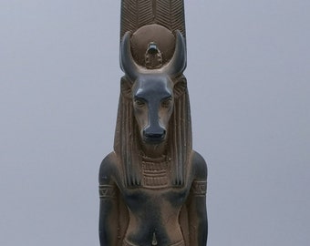 May include: A black statue of an Egyptian god with a bull's head, wearing a crown and a long, flowing wig.