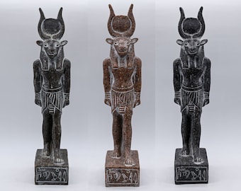 May include: Three stone statues of a bull-headed deity, each standing on a rectangular base. The statues are in shades of dark gray, reddish-brown, and black. The deity wears a headdress with a sun disc and horns, and a striped kilt. The base has hieroglyphs.
