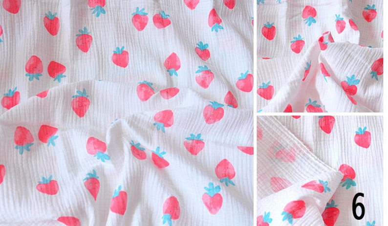 Puede incluir: Tela de muselina blanca con un patr&oacute;n repetido de fresas rosas con hojas azules. La tela es texturizada y tiene un aspecto arrugado.