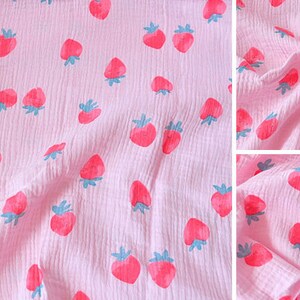 Puede incluir: Tela rosa con estampado de fresas blancas y azules. La tela es texturizada y tiene una sensaci&oacute;n suave y de gasa.