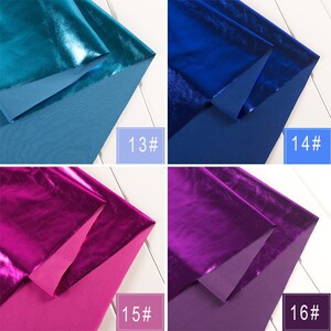 Op de afbeelding: Vier stofstalen in verschillende metallic kleuren. De stalen zijn dubbelgevouwen, waardoor de textuur en glans van de stof zichtbaar zijn. De kleuren zijn teal, blauw, roze en paars. De stalen zijn gemarkeerd met de nummers 13, 14, 15 en 16.