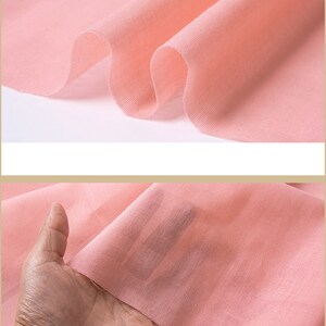 May include: A close-up of a soft, pink fabric. The fabric is smooth and has a slight sheen.