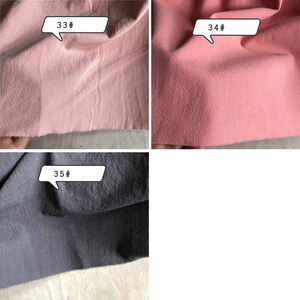 May include: Close-up of three fabric swatches. The top left swatch is a light pink colour. The top right swatch is a darker pink colour. The bottom swatch is a dark grey colour. Each swatch has a white label with a number on it. The top left label says "33#", the top right label says "34#", and the bottom label says "35#"