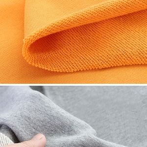 May include: Close-up of the inside of a yellow sweatshirt showing the soft, looped fabric. The second image shows the inside of a gray sweatshirt with a white lining.