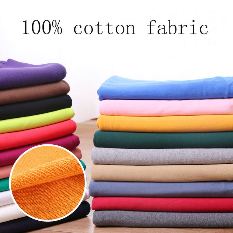 May include: A stack of 100% cotton fabric in various colors, including blue, pink, yellow, green, beige, red, and gray. The fabric is folded neatly and has a soft, textured surface.
