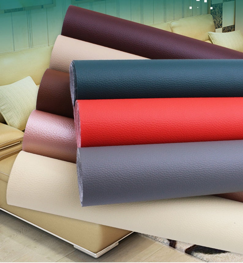 May include: A close-up of seven rolls of upholstery fabric in various colors, including beige, pink, gray, red, dark blue, and brown. The fabric has a textured, leather-like appearance.