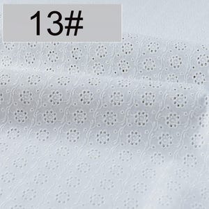 May include: A white fabric featuring an eyelet embroidery pattern with repeating floral motifs and delicate swirling vine details. The textile displays a consistent perforated design throughout, and a label marked 13# is visible.