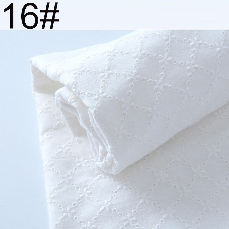 May include: A folded piece of white fabric featuring a repeating diamond pattern created with eyelet embroidery. The fabric has a textured surface with small circular cutouts forming the geometric design. The text 16# is visible in the corner.