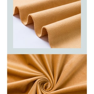 May include: Close-up of a soft, golden yellow velvet fabric. The fabric is folded and draped to show its texture and drape.