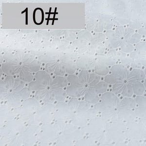 May include: A white fabric featuring an intricate eyelet embroidery pattern with repeating floral motifs and small circular cutouts. The textile displays a consistent, delicate design across its surface, marked with the text 10# in the corner.