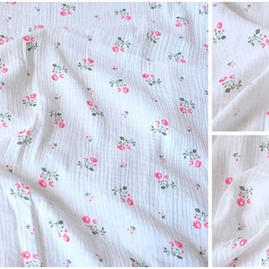 Puede incluir: Tela de algod&oacute;n blanca con un peque&ntilde;o estampado floral rosa. La tela es texturizada y tiene un aspecto ligeramente arrugado.