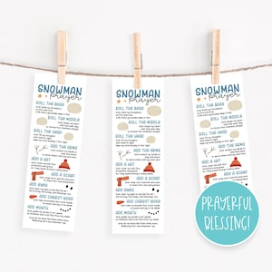 May include: Three white bookmarks with a snowman prayer printed on them, held by wooden clothespins. The text includes instructions to "Roll the Base," "Roll the Middle," and "Roll the Head." A blue circle with "Prayerful Blessing!" is on one.