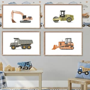 Op de afbeelding: Vier ingelijste prenten van bouwmachines: een graafmachine, een wals, een dumper en een bulldozer. De illustraties zijn in aquarel stijl, met een neutraal kleurenpalet, en worden getoond op een grijze muur.