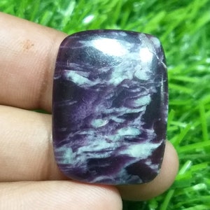 Peut inclure: Une pierre précieuse cabochon de couleur violette et blanche avec un motif tourbillonnant. La pierre précieuse est lisse et polie.