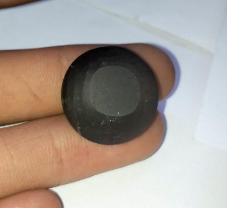 May include: A black, round, gemstone with a smooth, polished surface.